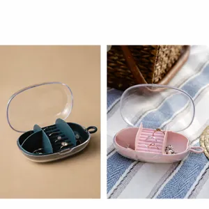 Portable clear cover jewelry box with multiple ring slots and compartments for travel storage.