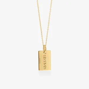 Detailed close-up of a minimalist gold rectangular tag pendant necklace with engraved date.