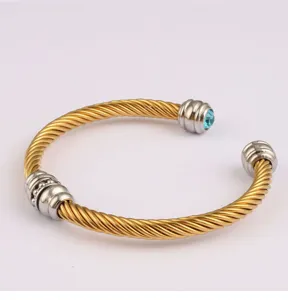 Gros plan d'un bracelet manchette torsadé bicolore chic avec des cristaux bleus fins.
