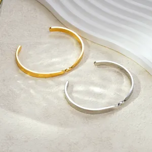 Vue détaillée de bracelets manchette ouverts torsadés en acier inoxydable doré et argenté.
