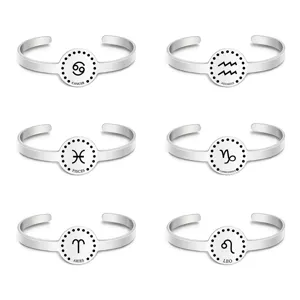 Detail view of silver stainless steel zodiac cuff bracelets featuring engraved symbols.