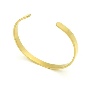 Gros plan bracelet jonc en métal doré, surface polie lisse au design minimaliste.