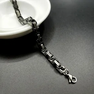 Detailed shot of heavy stainless steel Byzantine king chain bracelet for men in silver and dark gray.