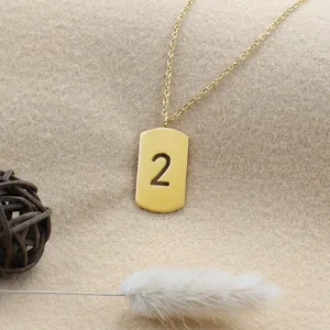 Gold-plated dog tag pendant necklace featuring a cutout number two detail, close-up view.