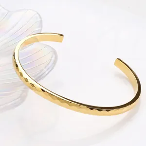 Bracelet jonc ouvert plaqué or 18K avec finitions facettées, bijou élégant de haute texture.