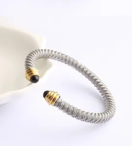 Vue de détail du bracelet manchette en fil d'acier inoxydable avec accents dorés et perles.