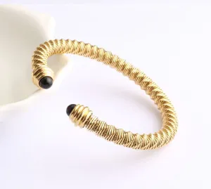 Gros plan détaillé du bracelet manchette ouvert en câble d'acier inoxydable doré perles.