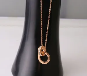Rose gold titanium steel necklace for women with double ring and cubic zirconia stones.