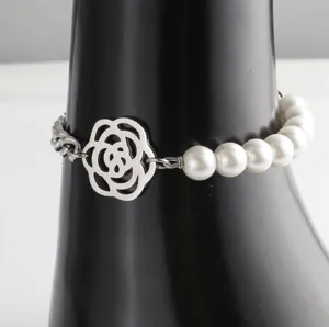 Camellia flower metal pendant bracelet detail featuring shiny white pearls and steel chain.