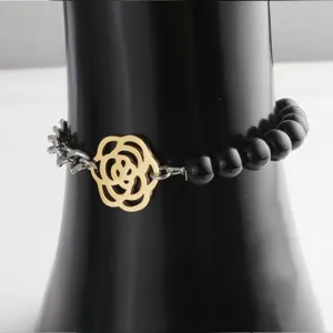 Detail view of titanium steel bracelet featuring black beads, metal chain and gold flower charm.