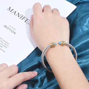 Bracelet manchette en câble torsadé en acier inoxydable avec des pierres bleues.