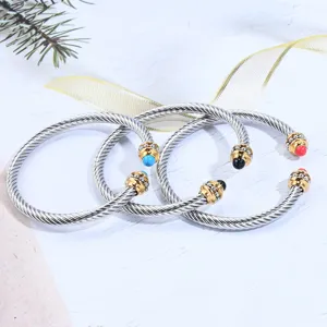 Bracelet manchette tordu en acier inoxydable avec finitions dorées et perles de pierre élégant.