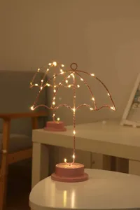 Vista detallada de la lámpara de mesa LED rosa con forma de paraguas, luz ambiental acogedora.