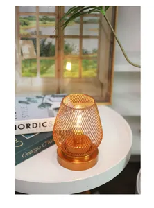 Primer plano detalle de la moderna lámpara de mesa LED de malla oro rosa sobre mesa redonda blanca.