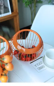Cestino per frutta in filo di metallo arancione con pomodorini, elegante decorazione nordica.