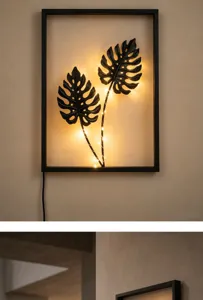 Dettaglio in primo piano della moderna lampada da parete in ferro nero con foglie di monstera.