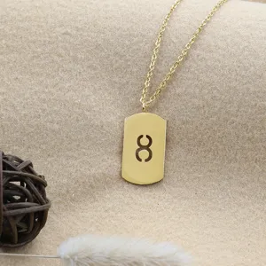 Detailed shot of a gold-plated dog tag pendant necklace with a cutout geometric symbol.