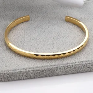 Bracelet jonc ouvert facetté plaqué or avec une texture géométrique élégante en détail.