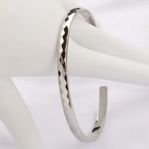 Bracelet jonc ouvert facetté vue de détail, design de bijoux en métal argenté brillant.