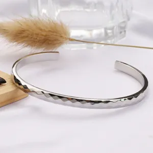Gros plan détaillé sur un bracelet manchette en métal argenté doté de superbes facettes.