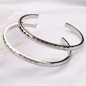Vue detaillee de bracelets manchette ouverts facettes en acier inoxydable, design geometrique.