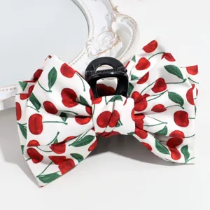 Close-up detail of cute cherry print fabric hair claw bow, sweet daily styling accessory.
