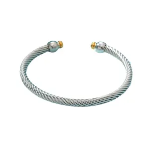 Bracelet manchette torsadé en acier inoxydable avec embouts dorés pour femmes élégantes.