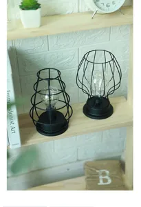 Detailaufnahme von schwarzen Drahtgitter-LED-Tischlampen auf einem Holzregal für die Deko.