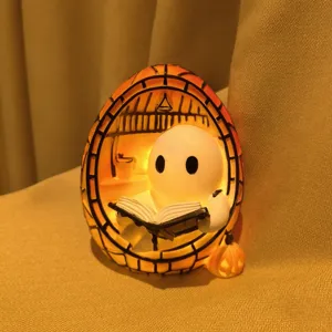 Primo piano del fantasma di Halloween che legge un libro in una simpatica luce notturna in resina.