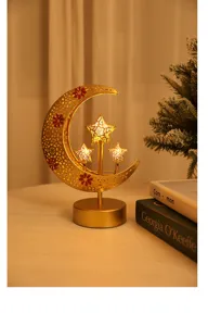Close-up of golden iron hollow moon and star LED decorative lamp, warm festive ambient lighting.