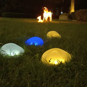 Detail van solar LED steenverlichting met kleurrijk lichteffect op het gazon in de nacht.
