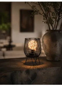 Detailed shot of retro metal wireframe table lamp with warm LED fairy lights in room.