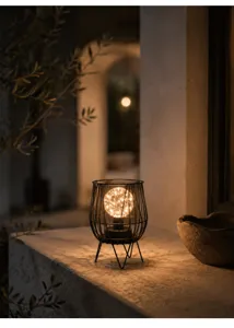 Close up of rustic decorative LED night light with warm string lights in metal wire frame.