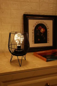 Creative black wire LED table lamp detail shot, rustic retro night light for cozy home decor.