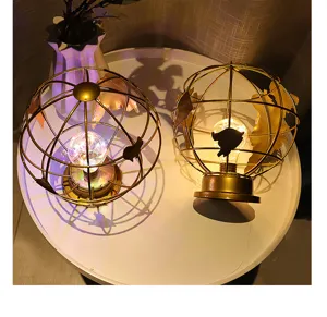 Close-up van decoratieve ijzeren wereldbol nachtlamp met warme LED op witte tafel.