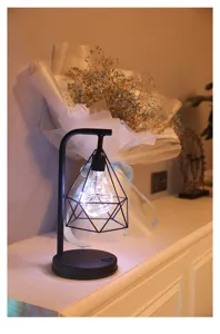 Detailopname van de moderne zwarte ijzeren geometrische tafellamp met warme LED-verlichting.