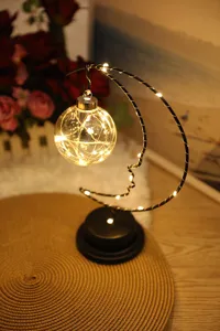 Cozy moon night light close-up showing warm LED string lights inside the hanging glass ball.