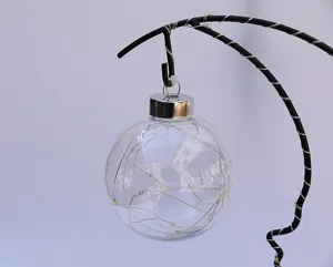 Detailed shot of a transparent glass ball ornament with inner LED fairy lights on a stand.