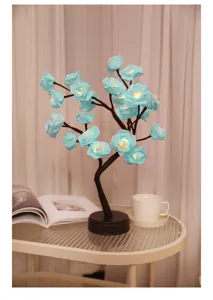 Detailopname van blauwe LED rozenboomlamp op tafel met boek en kopje, gezellige sfeer- en nachtlamp.