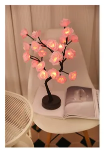 Gedetailleerd overzicht van de romantische roze rozenboom LED lamp met warm licht op een witte stoel.