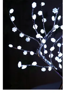 Gedetailleerd close-up van romantische LED boomverlichting met witte sneeuwvlokbloemen.