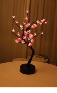 Detailopname van een prachtige LED kersenbloesem boomlamp die warm licht geeft op een tafel.