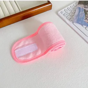 Detalle de diadema de spa de felpa rosa que muestra tela de toalla y cierre de velcro.