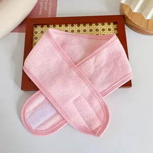 Vista detallada de la suave diadema de rizo rosa con cierre de velcro ajustable para maquillaje.