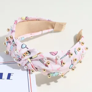 Serre-tête en tissu noué rose avec de jolis imprimés scolaires et des perles artificielles.