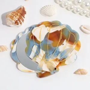 Detail view of the portable seashell folding makeup mirror with elegant golden lines and resin.