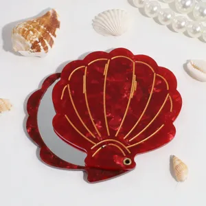 Red shell folding makeup mirror with gold lines, compact portable travel cosmetic mirror detail.