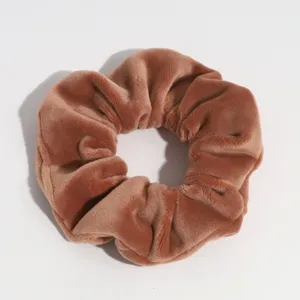 Close-up detail shot showing the soft brown velvet texture of the chic hair scrunchie.