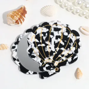 Detail view of a black and white shell folding makeup mirror, compact and portable design.