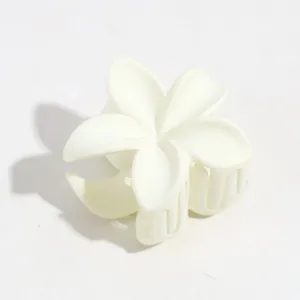 Nahaufnahme einer weißen, matten Blumen-Haarklammer, kleine Haifischklammer mit feinem Blumendetail.